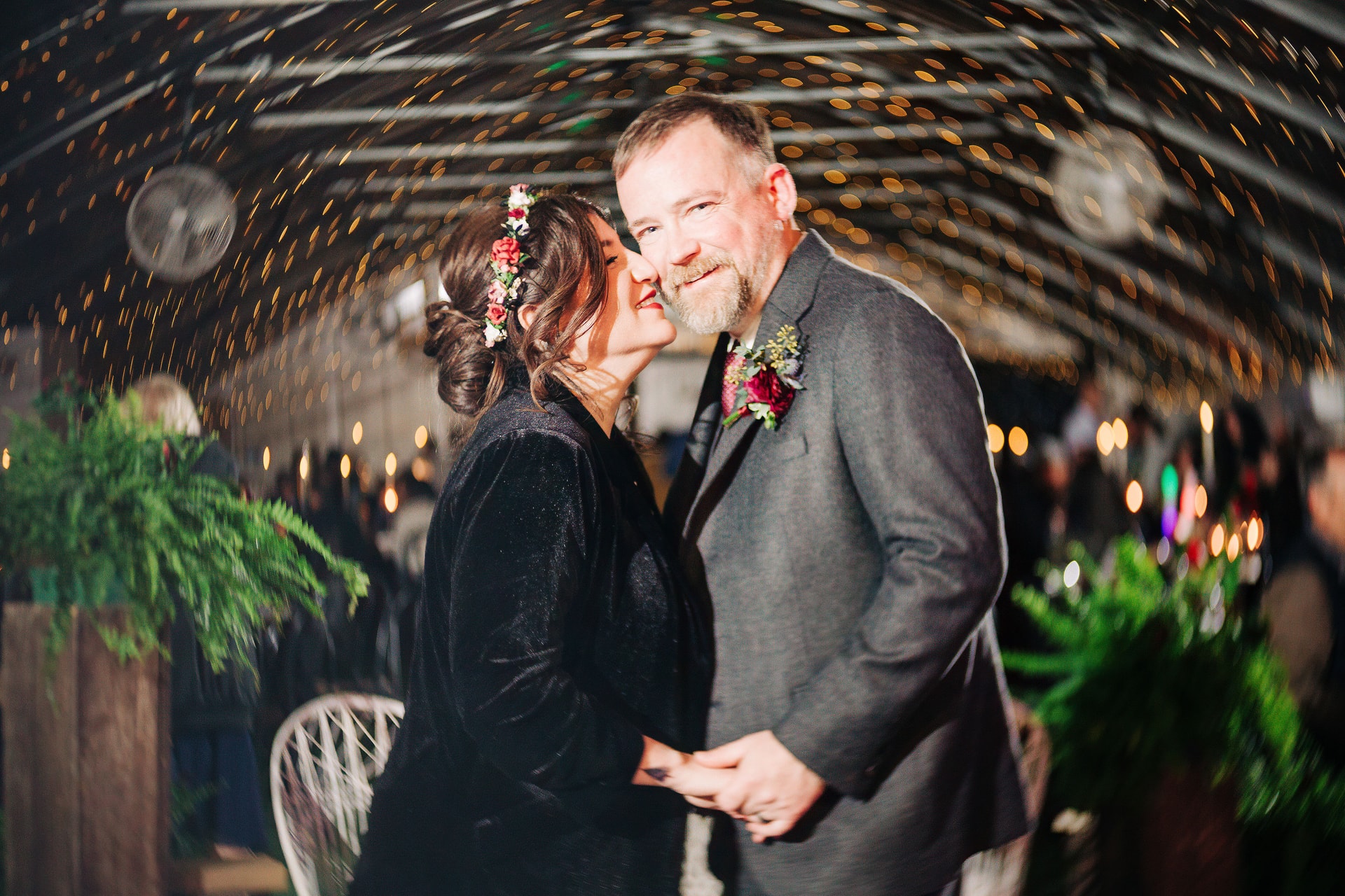 Jenn gives Billy a kiss on the cheek as they are surrounded by swirling bokeh lights and colors.
