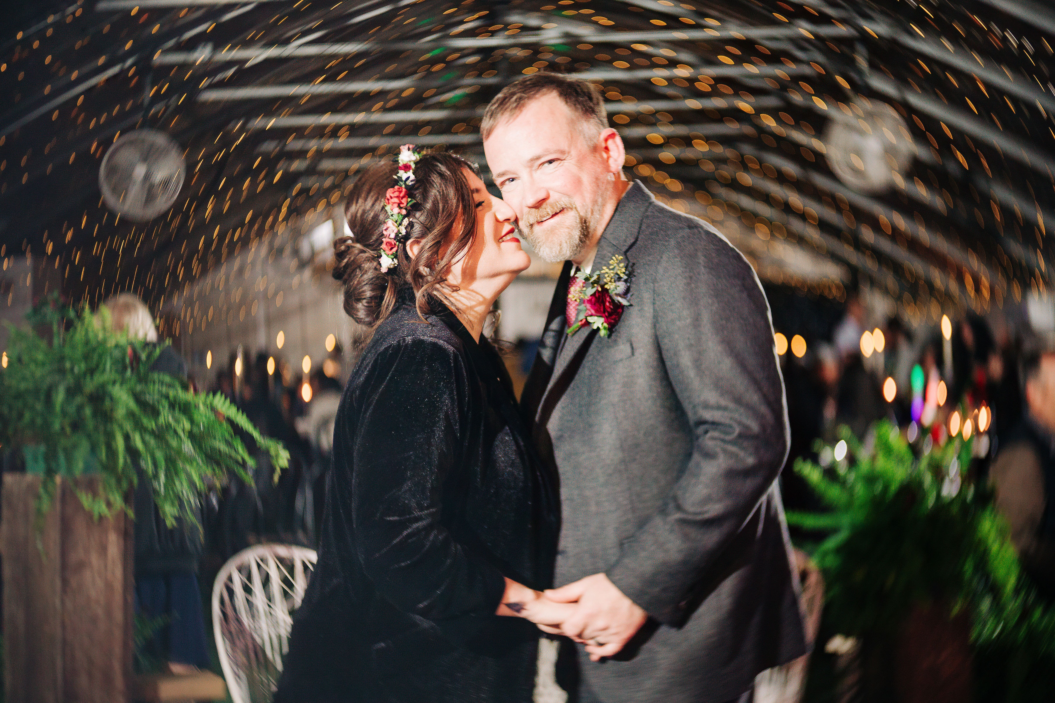 Jenn gives Billy a kiss on the cheek as they are surrounded by swirling bokeh lights and colors.
