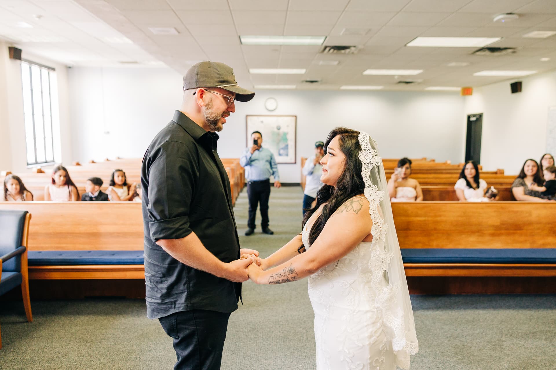 A couple exchanging vows in the Travis County courtroom, natural window light across their faces