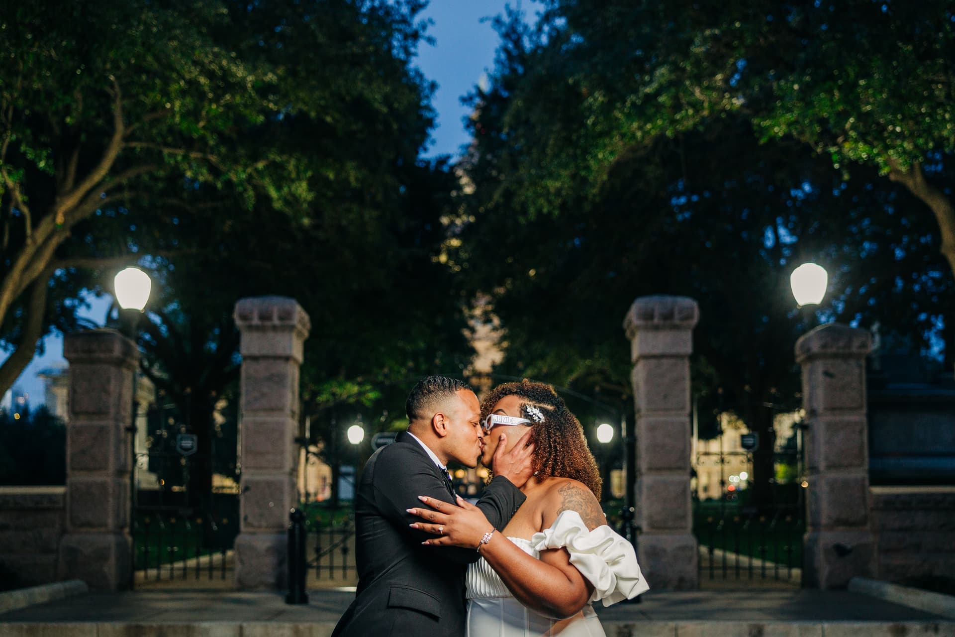 Couple on the Capitol grounds, the dome rising above the tree line behind them
