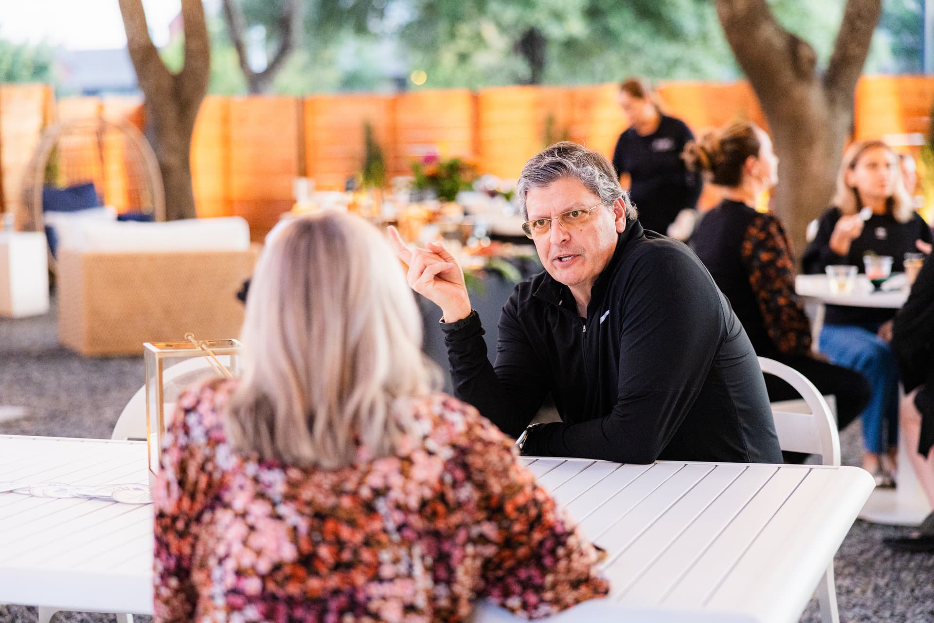 natural candid photo of a man and woman having conversation at a netoworking event, sitting, outside