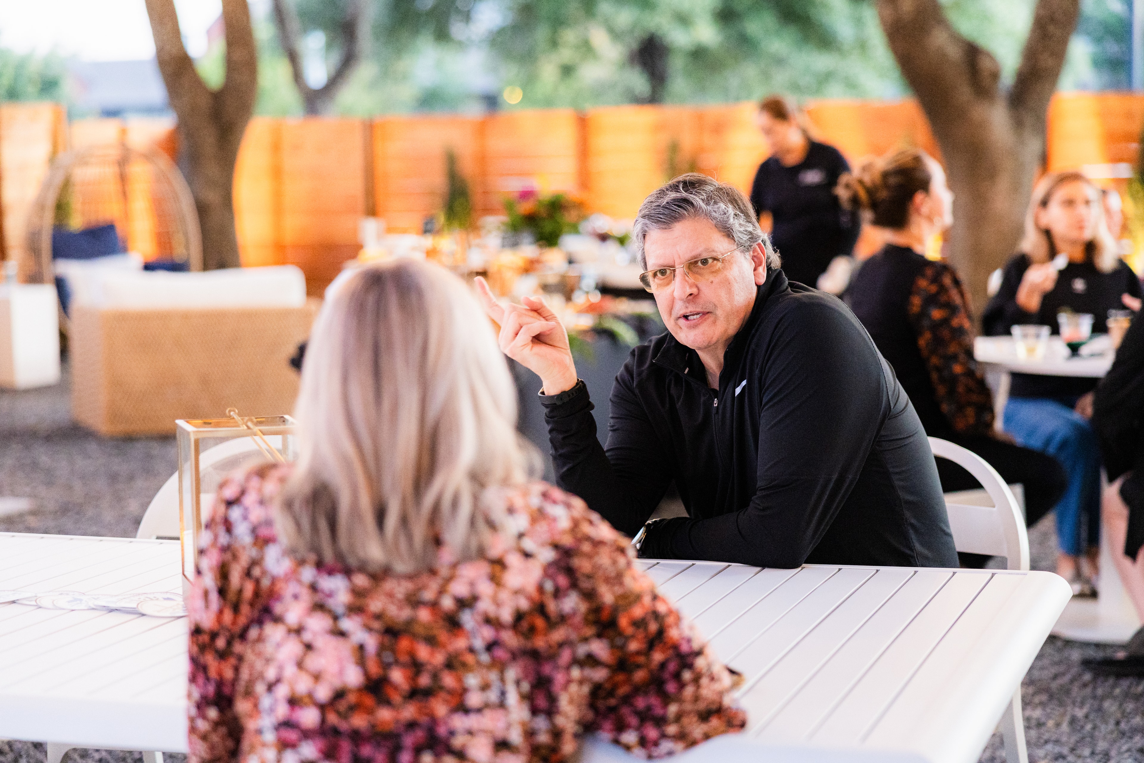 natural candid photo of a man and woman having conversation at a netoworking event, sitting, outside