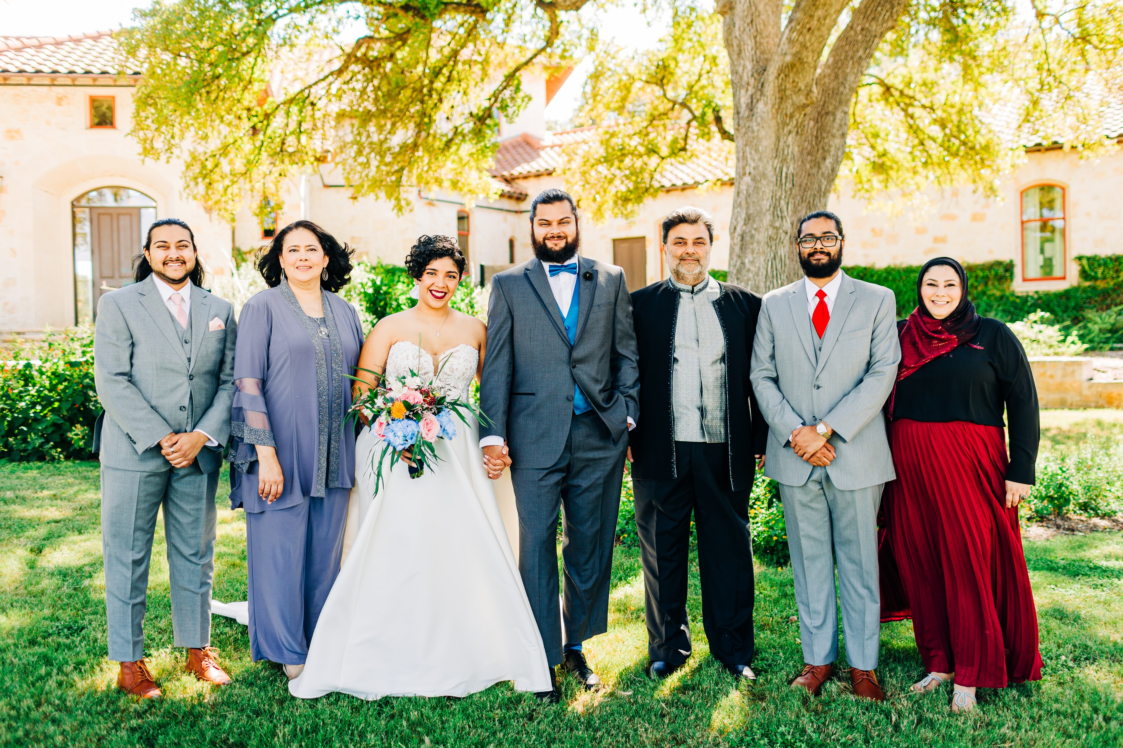 a warm group portrait of a bride and groom with their closest family members. the lighting is soft and natural, and all people in the photo appear relaxed, comfortable, and stress free.