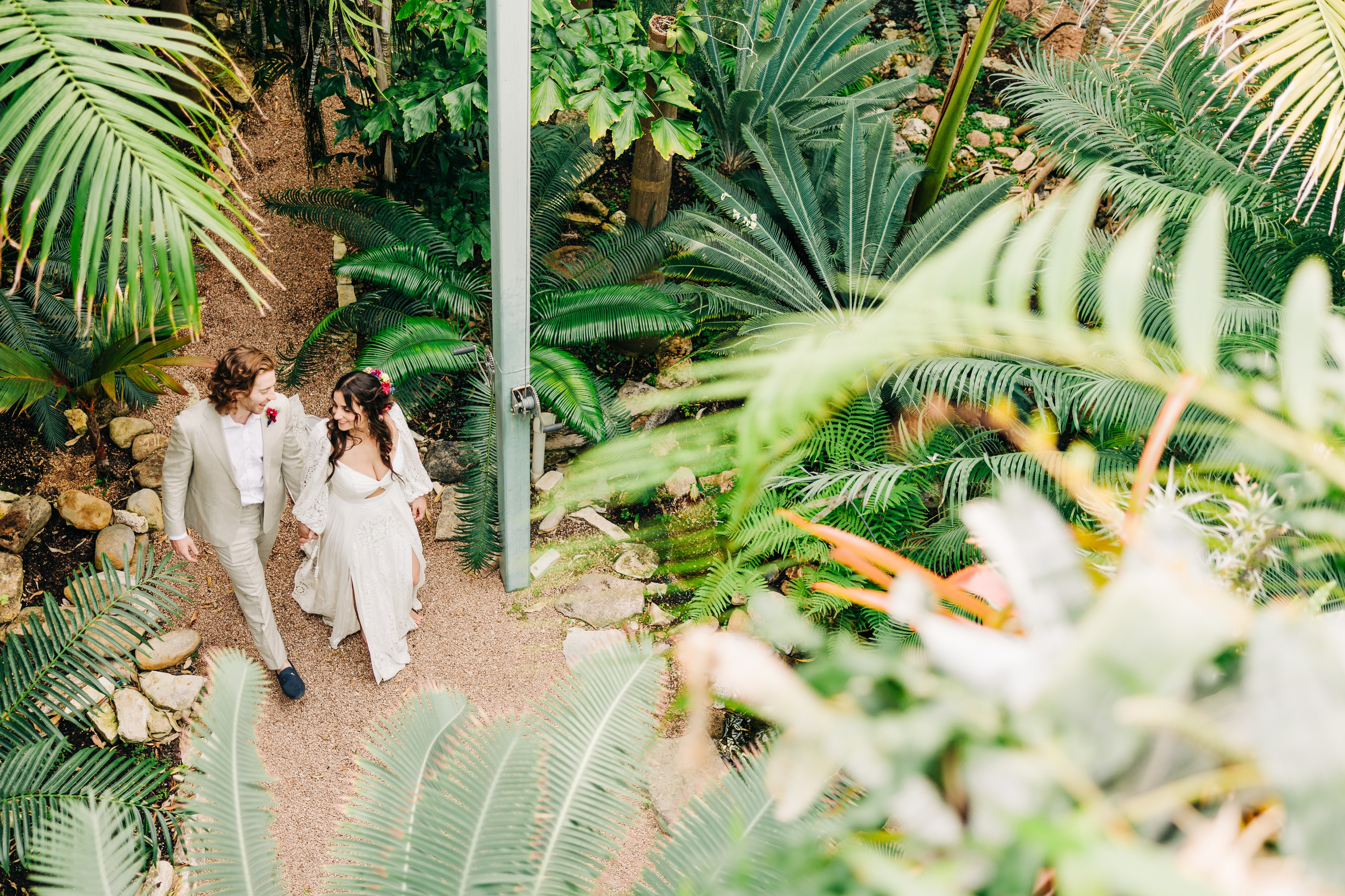 Bride and groom portrait surrounded by lush tropical plants inside the Greenhouse at Driftwood, natural light filtering through the glass ceiling