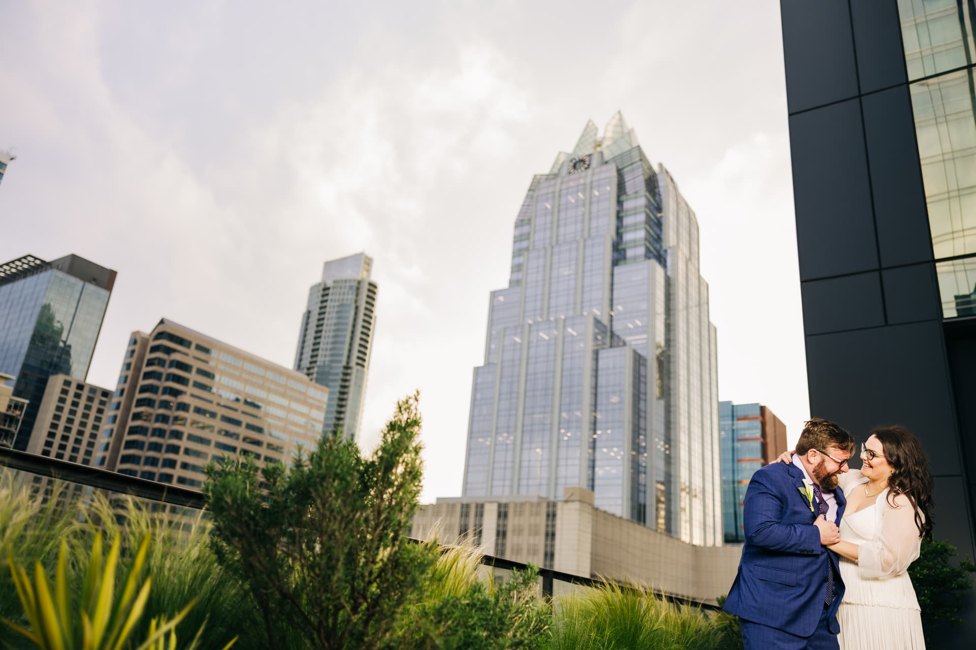 Rooftop couples portrait at Thompson Austin hotel with city skyline backdrop and warm golden-hour light on the couple