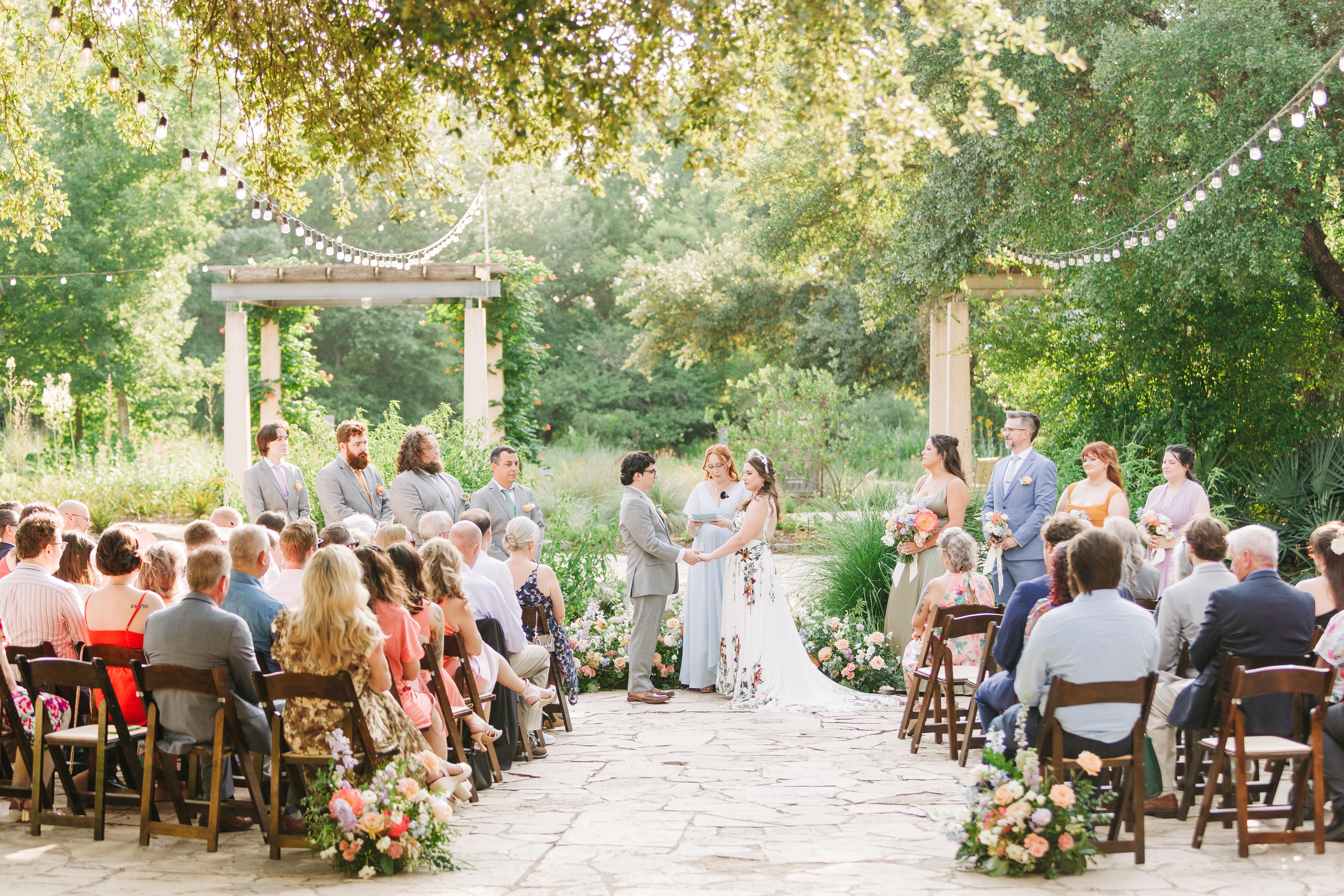 Wedding ceremony in front of the pond at the Lady Bird Johnson Wildflower Center, lush botanical gardens framing the couple at sunset